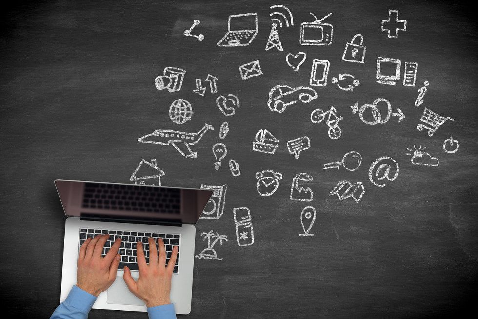 a photo of a person typing on a laptop with objects on a chalkboard