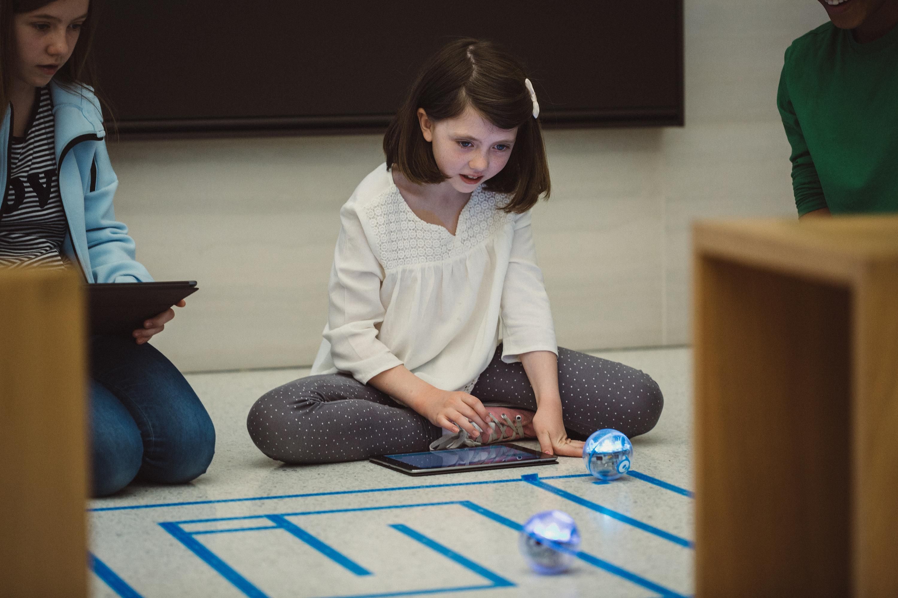 Photo of a little girl sitting on the floor playing with robots