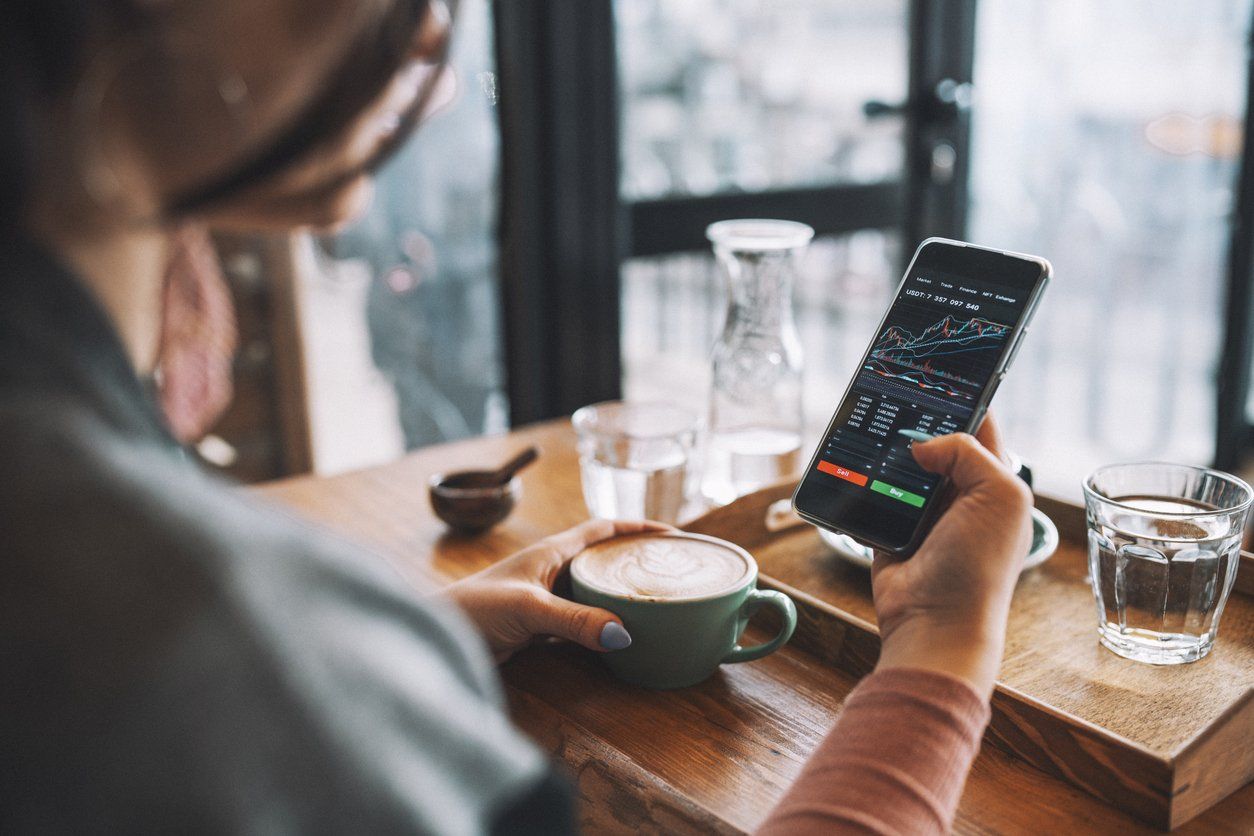 a photo of a woman on her smartphone investing in cryptocurrency.