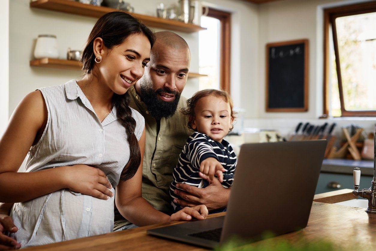 a photo of a father and expecting mother looking at a computer