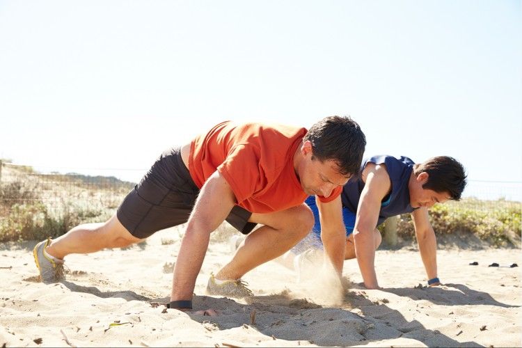 two men workiing out on the beach wearing fitness trackers photo