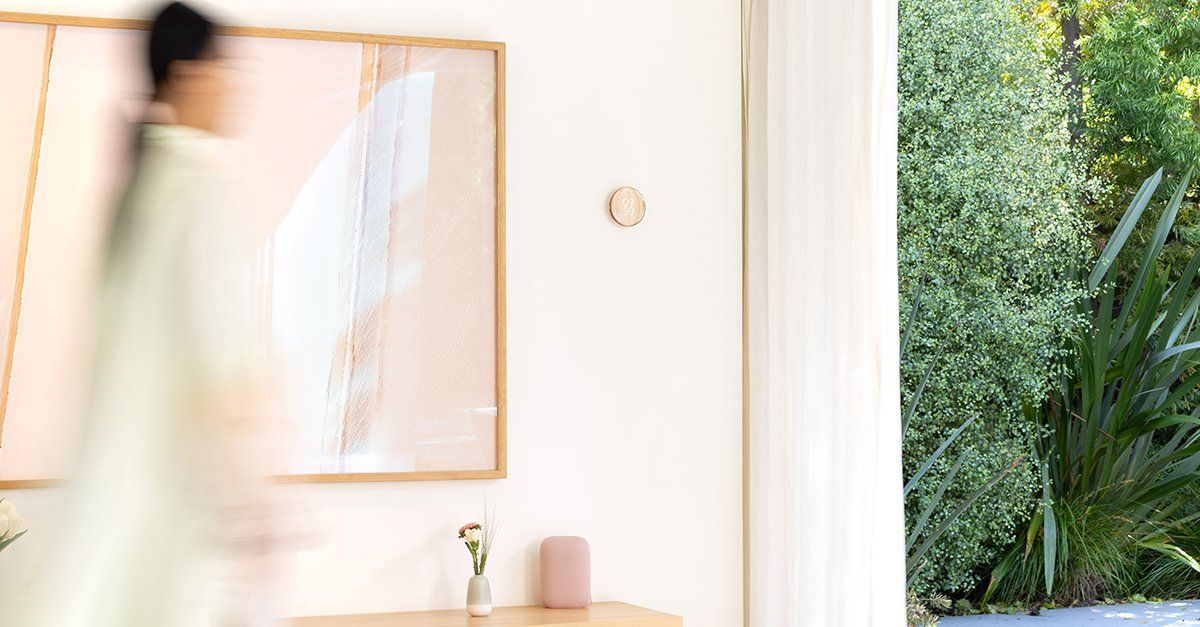 a photo of a woman walking infront of new Nest Learning Thermostat which reacts to her movements