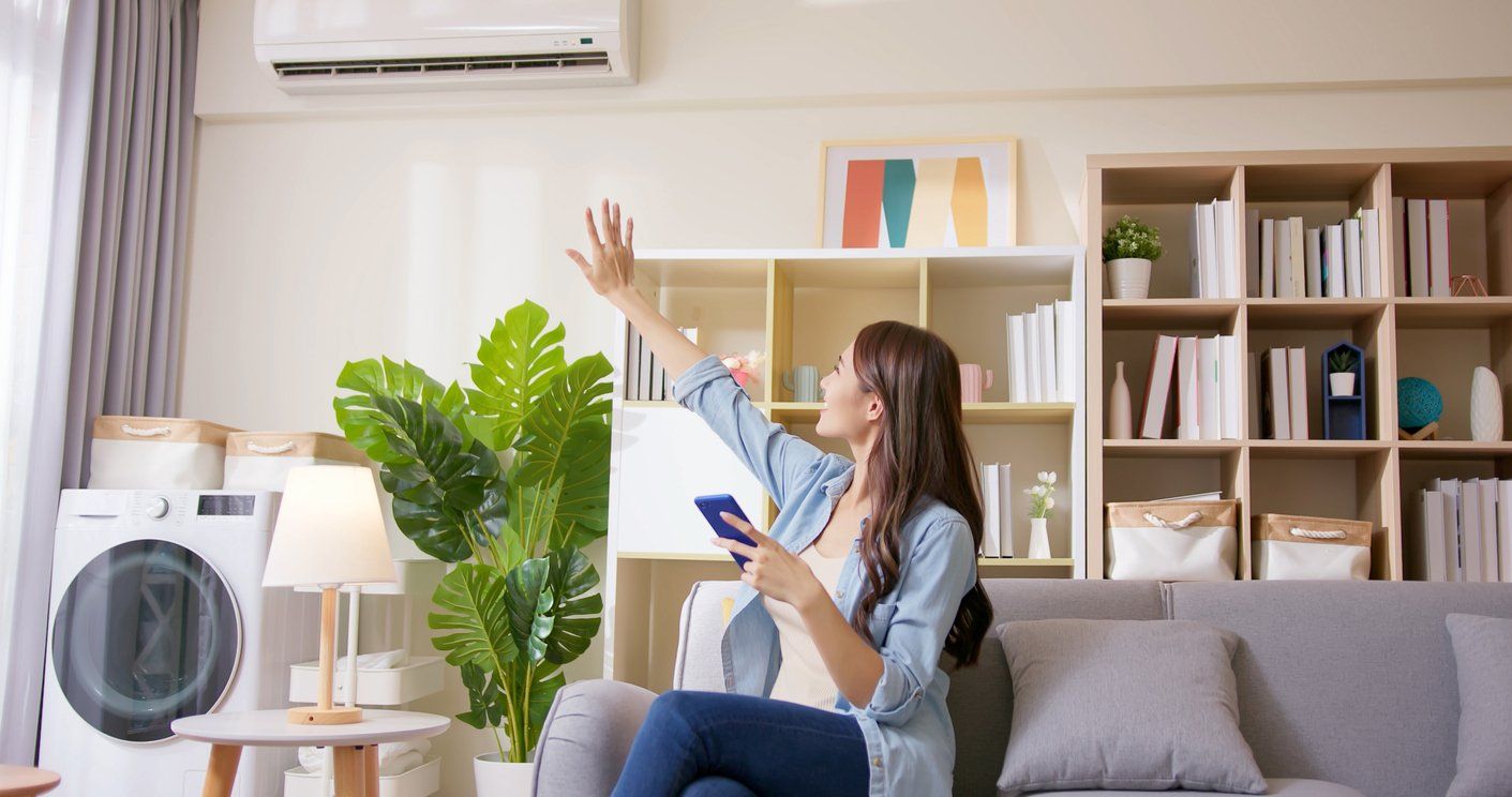 a woman in a room with her smartphone controlling her smart AC unit.