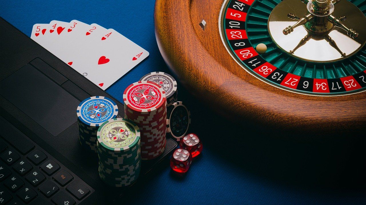 a photo of a roulette wheel, chips, cards, dice and a keyboard