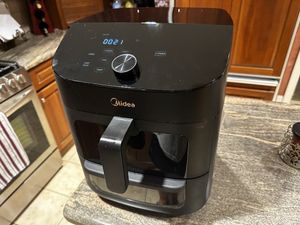 a photo of Midea Two-Zone 11QT Air Fryer Oven cooking on a countertop in a kitchen