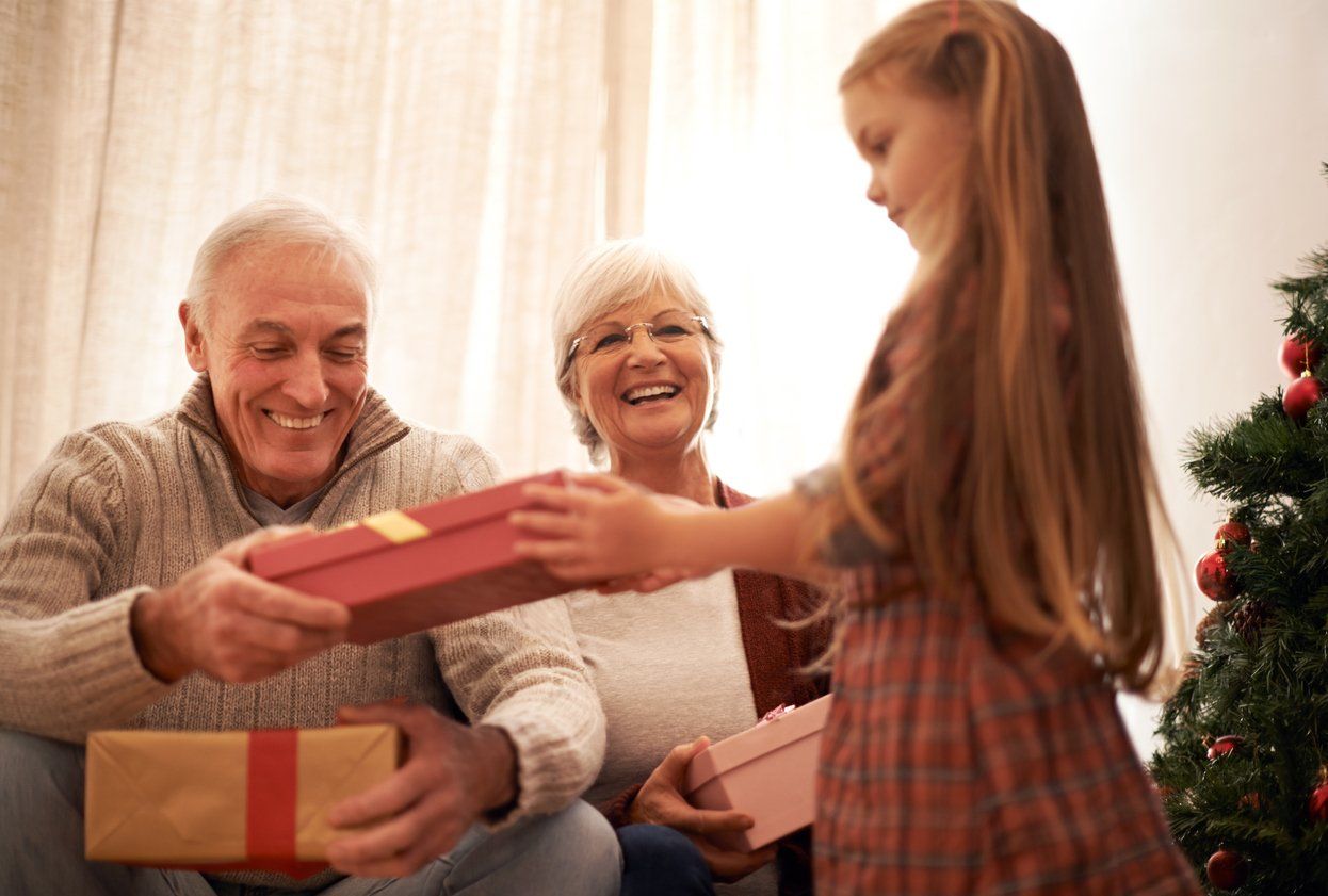 a photo of a little girl bringing in the gifts for her grandparents