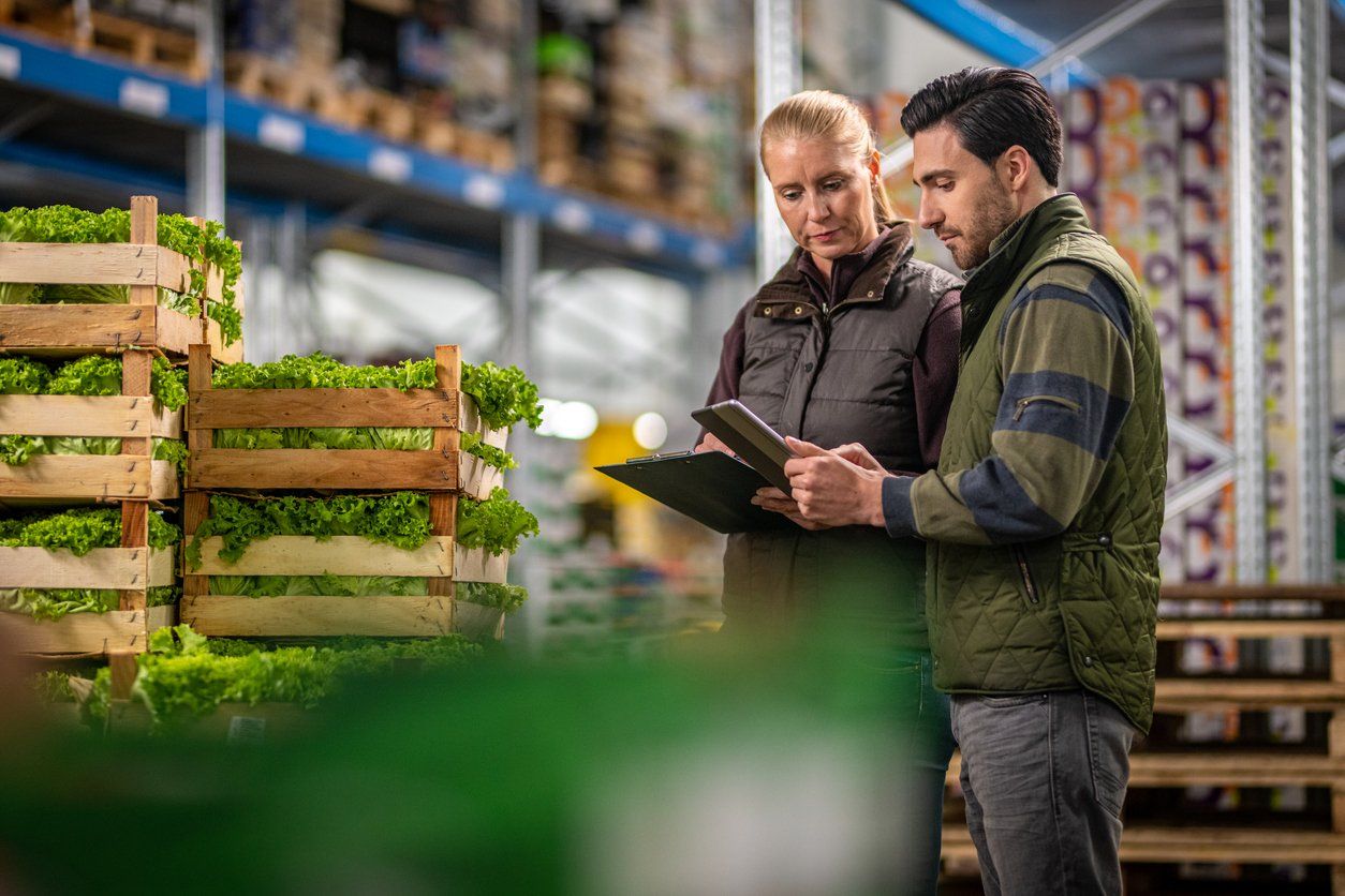 two works checking product in a warehouse and looking at electronic orders on their tablets