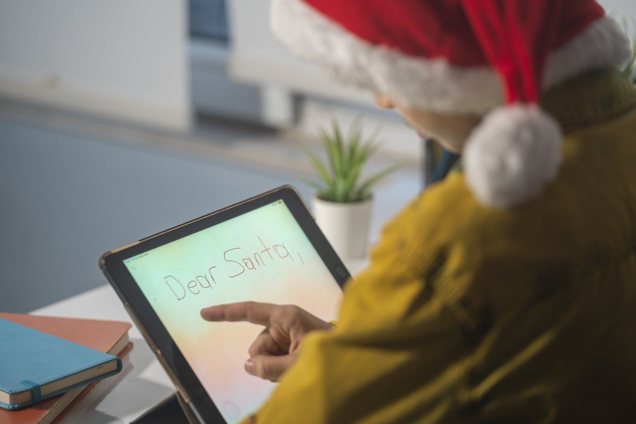 Photo Of Boy With Santa Hat Using Digital Tablet For Texting Santa Claus stock photo